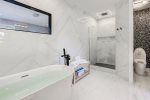 Master ensuite offers a lavish freestanding bathtub & frameless shower